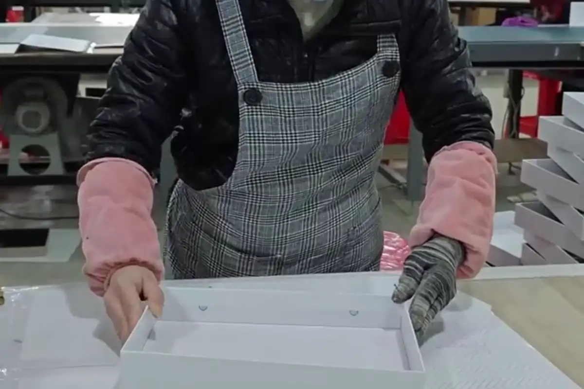 Worker checking a white rigid box sample before small-batch production