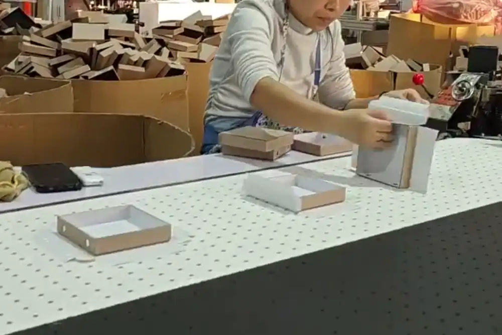 Worker assembling and inspecting a real paper box sample