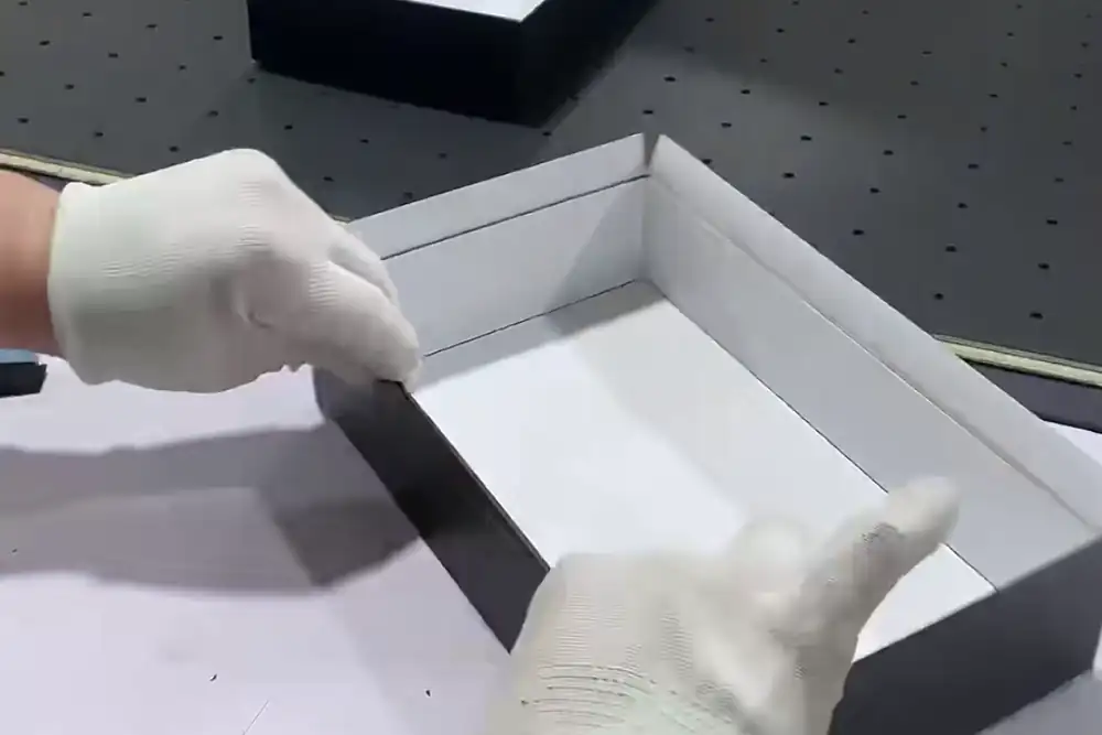 Worker completing the final assembly of a real lid-and-base gift box